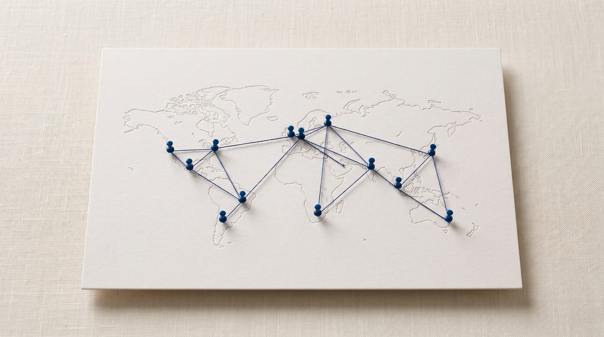 Paper world map with navy pins linked by thread